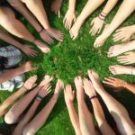 a circle of hands and feet from a group of friends, on luscious grass.