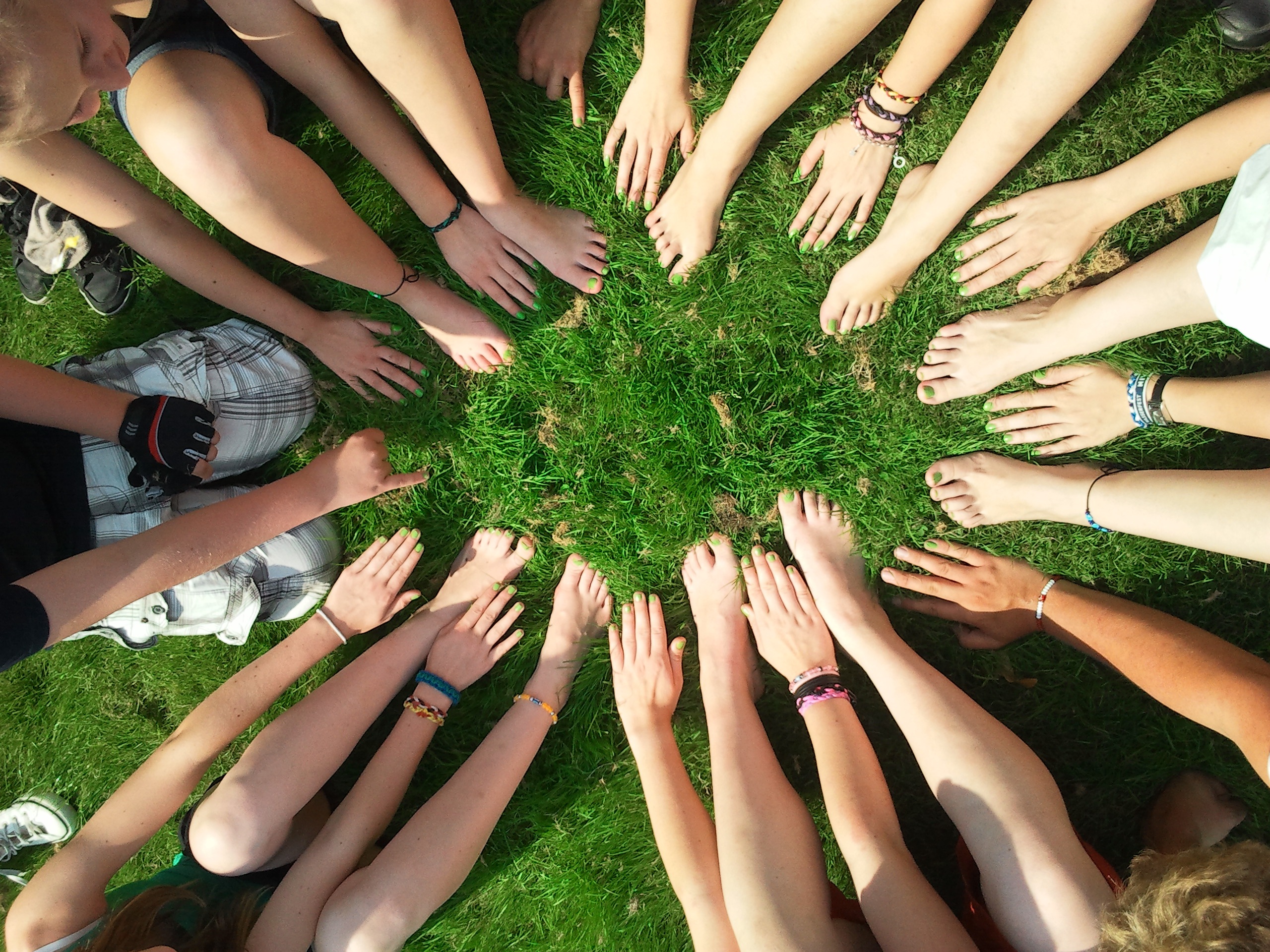 a circle of hands and feet from a group of friends, on luscious grass.