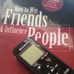 A copy of How to Win Friends and Influence People sits under a Sony audio recorder